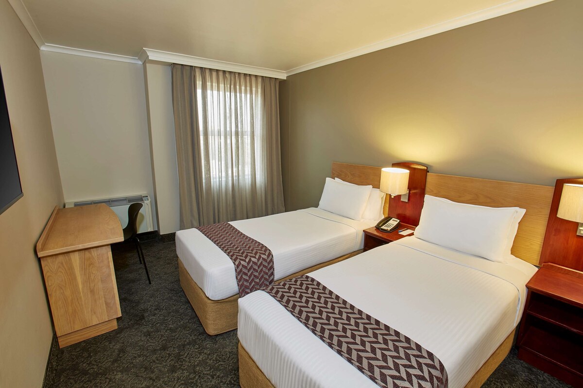 Une chambre d’hôtel avec deux lits, un bureau et une chaise.