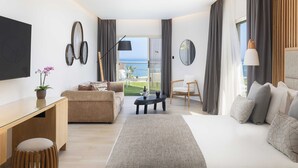 A modern hotel room with a large bed, a sofa, a desk, and a view of the sea. - Atlantica Bay Hotel - Adults Only (Limassol)