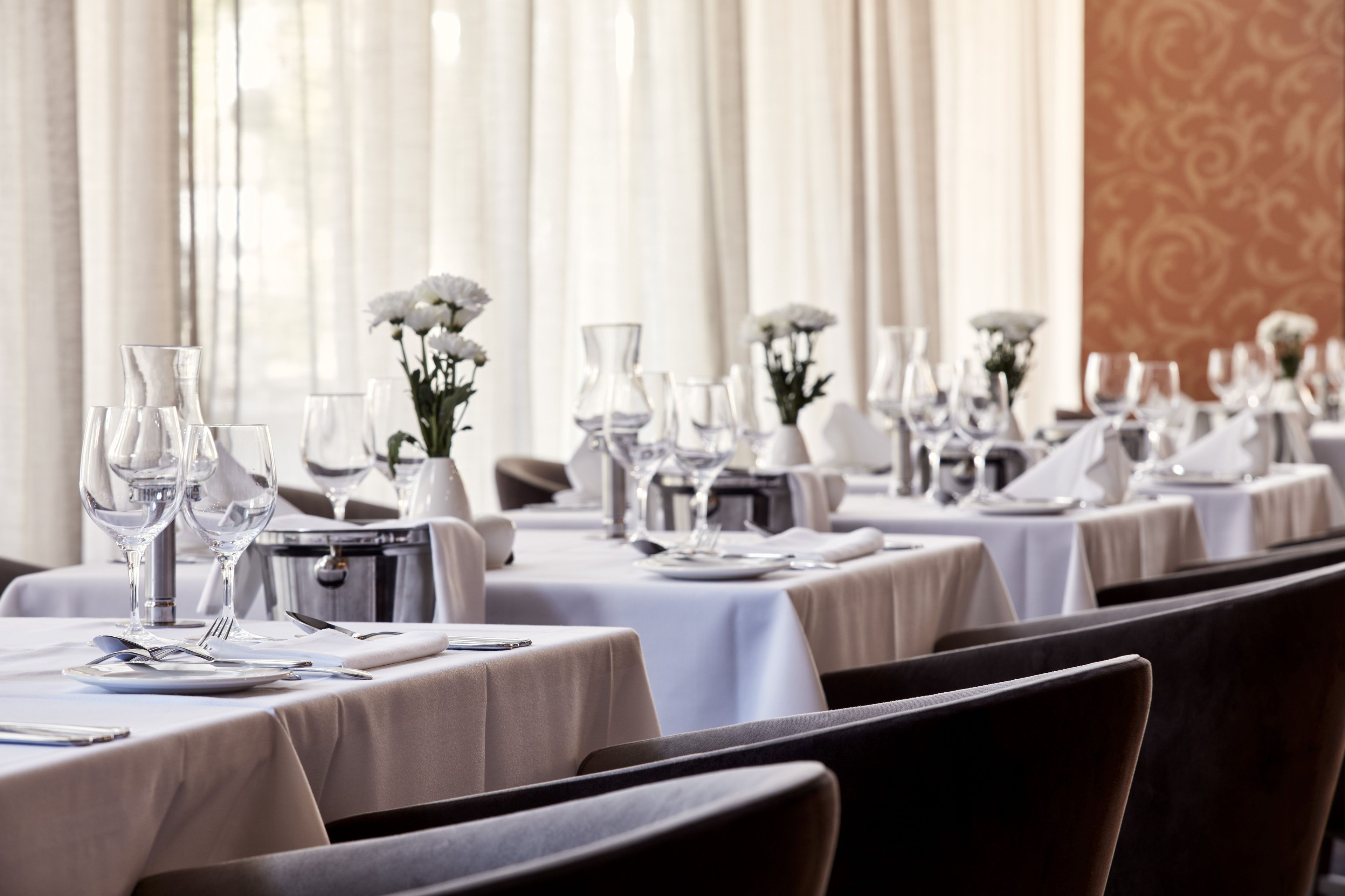 Un ristorante con tavoli apparecchiati per la cena, caratterizzato da tovaglie bianche e bicchieri.