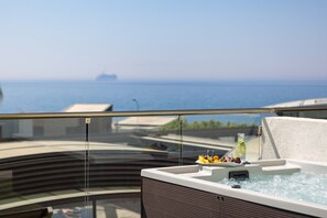 A hot tub with a clear view of the sea and a ship in the distance.