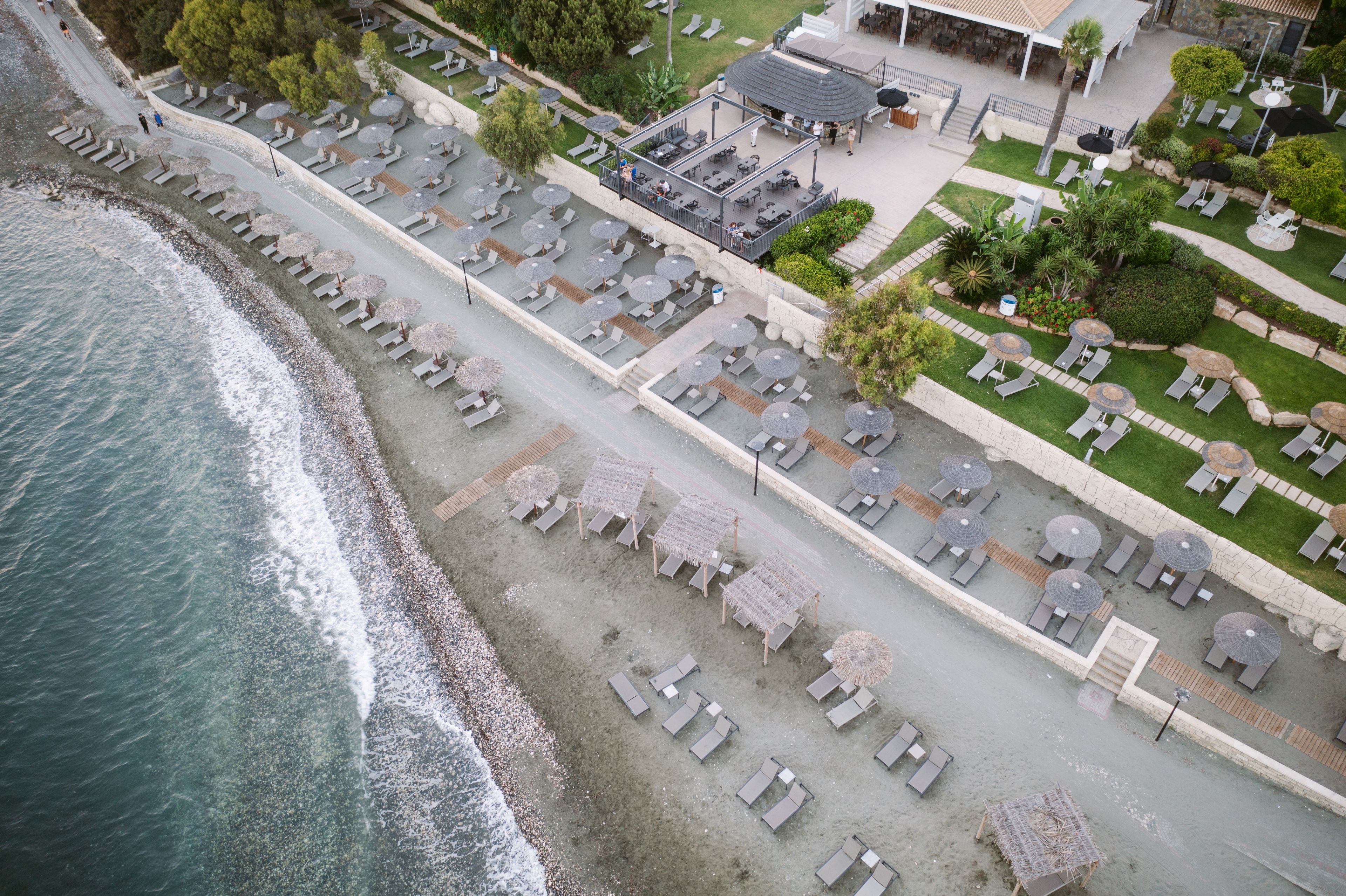 Eine Vogelperspektive eines Strandanlieger-Resorts mit mehreren Liegebereichen, einem Pool und einem Restaurant.