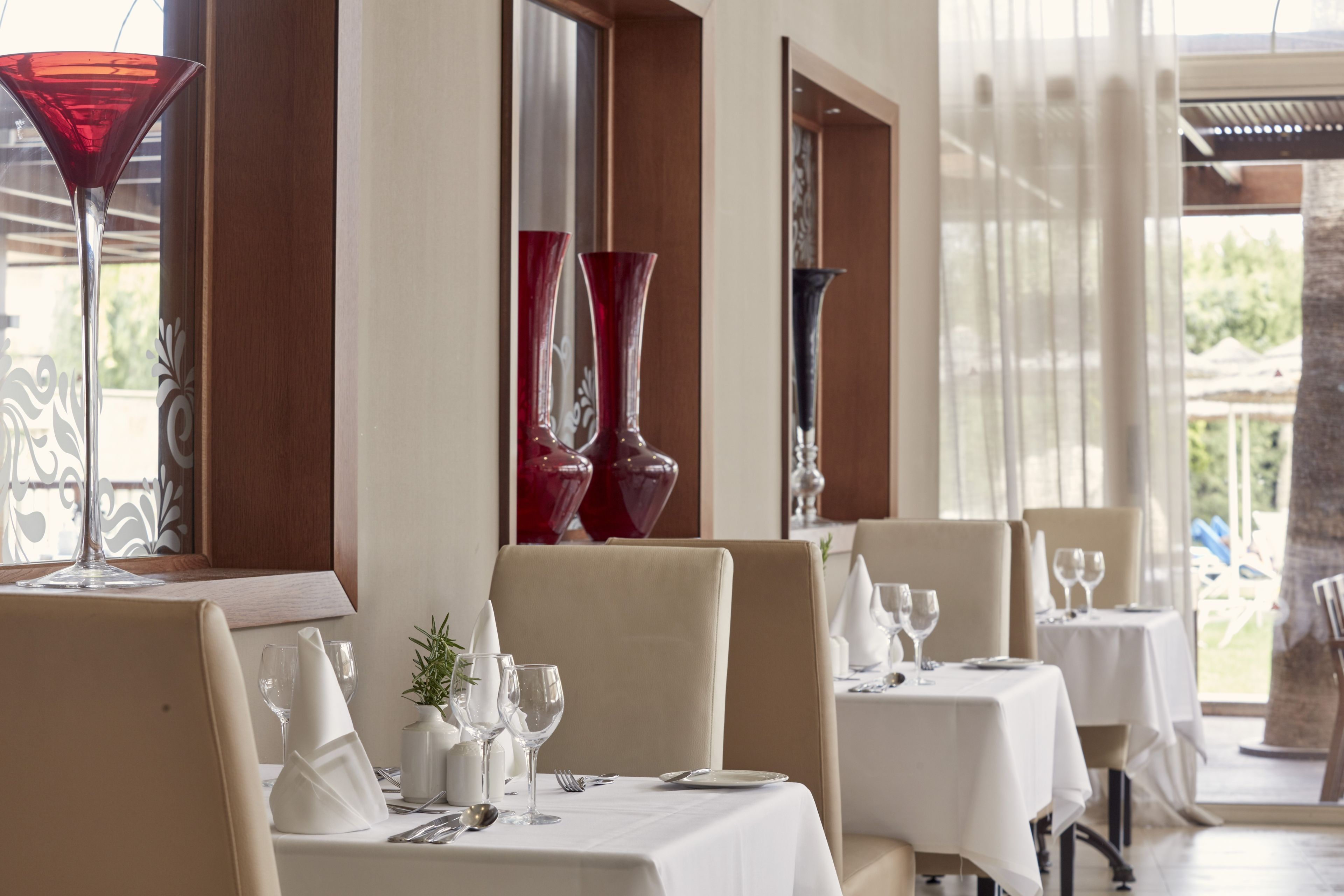 A restaurant with tables set for dining, featuring a view of the outdoors.