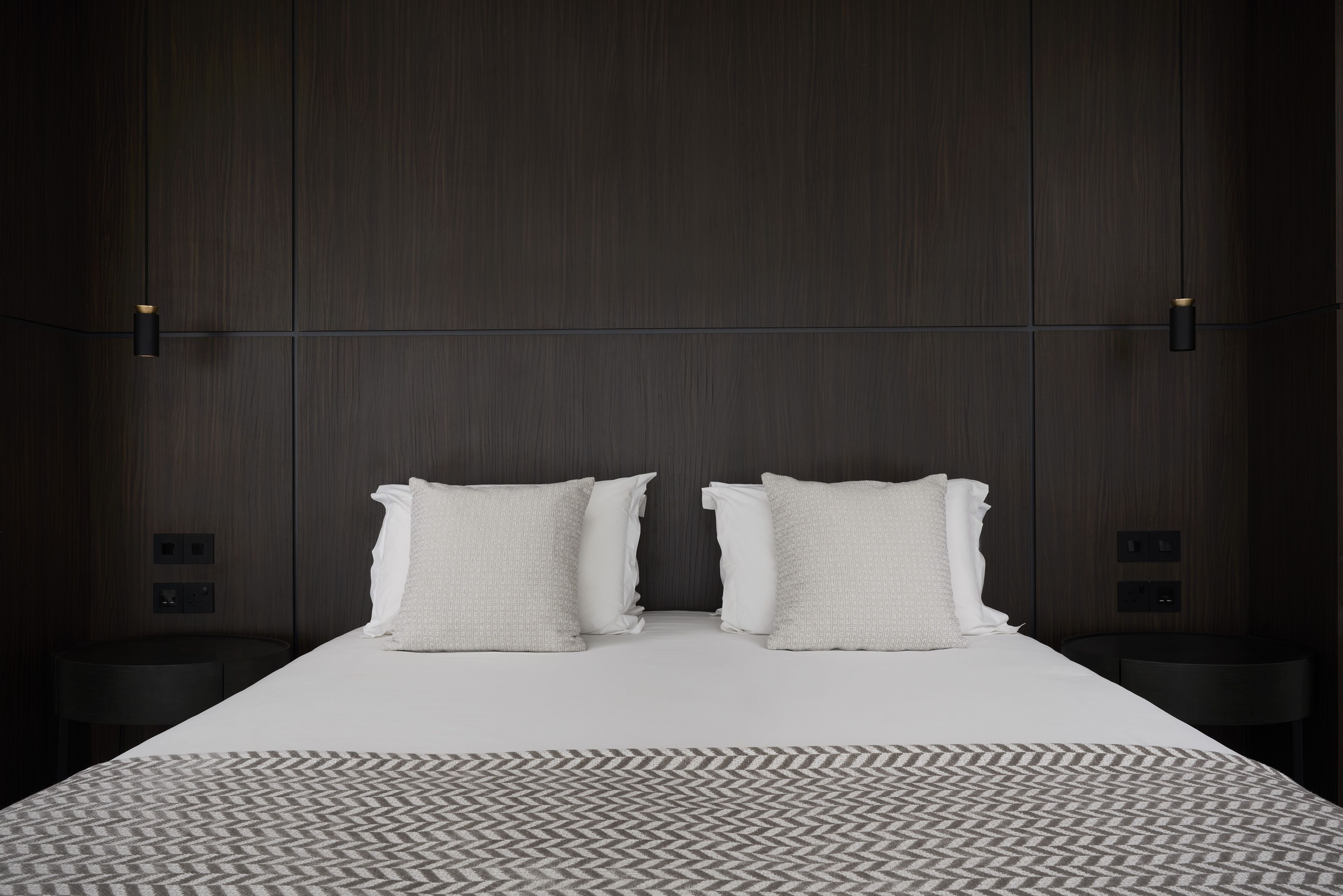 Une chambre d’hôtel moderne avec un grand lit, deux tables de chevet et un tapis à motifs.