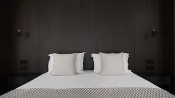 Une chambre d’hôtel moderne avec un grand lit, deux tables de chevet et un tapis à motifs.