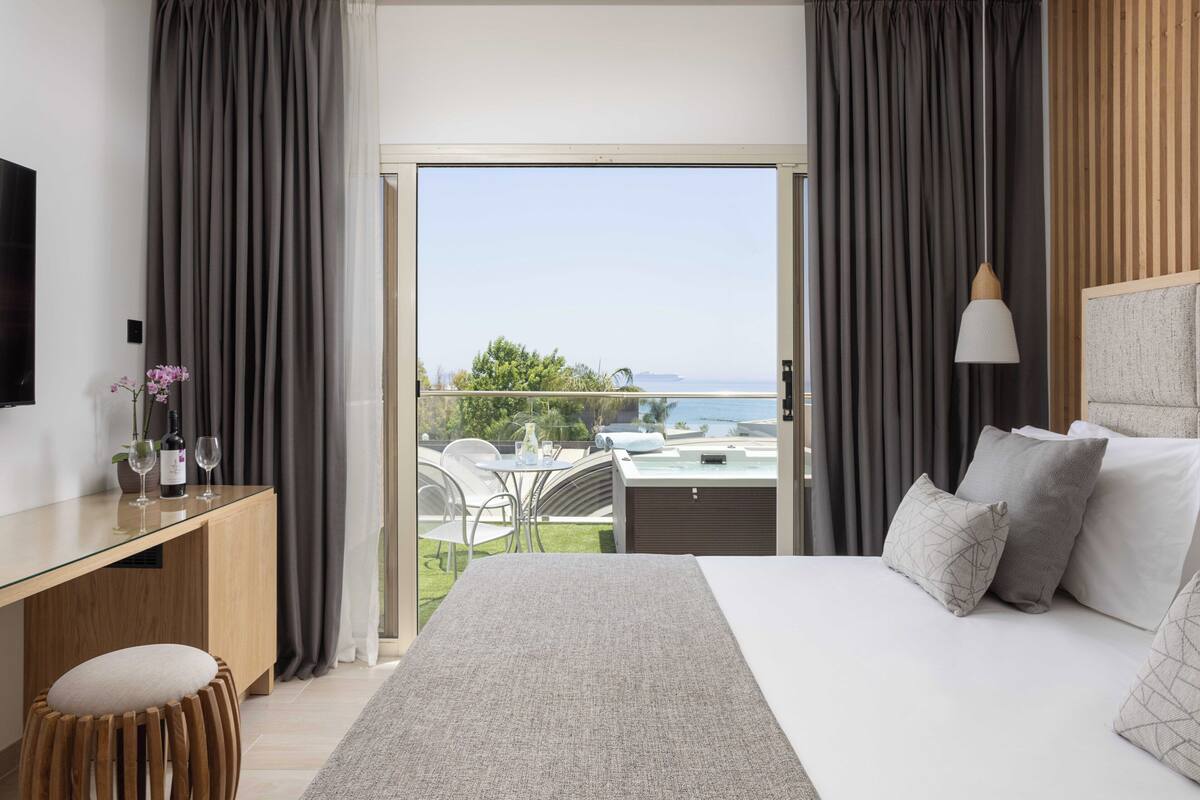 Een moderne hotelkamer met een groot bed, een bureau en uitzicht op zee.