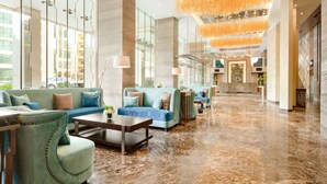 Un'ampia hall con pavimento in marmo, diverse zone relax con divani e poltrone, e un grande lampadario.