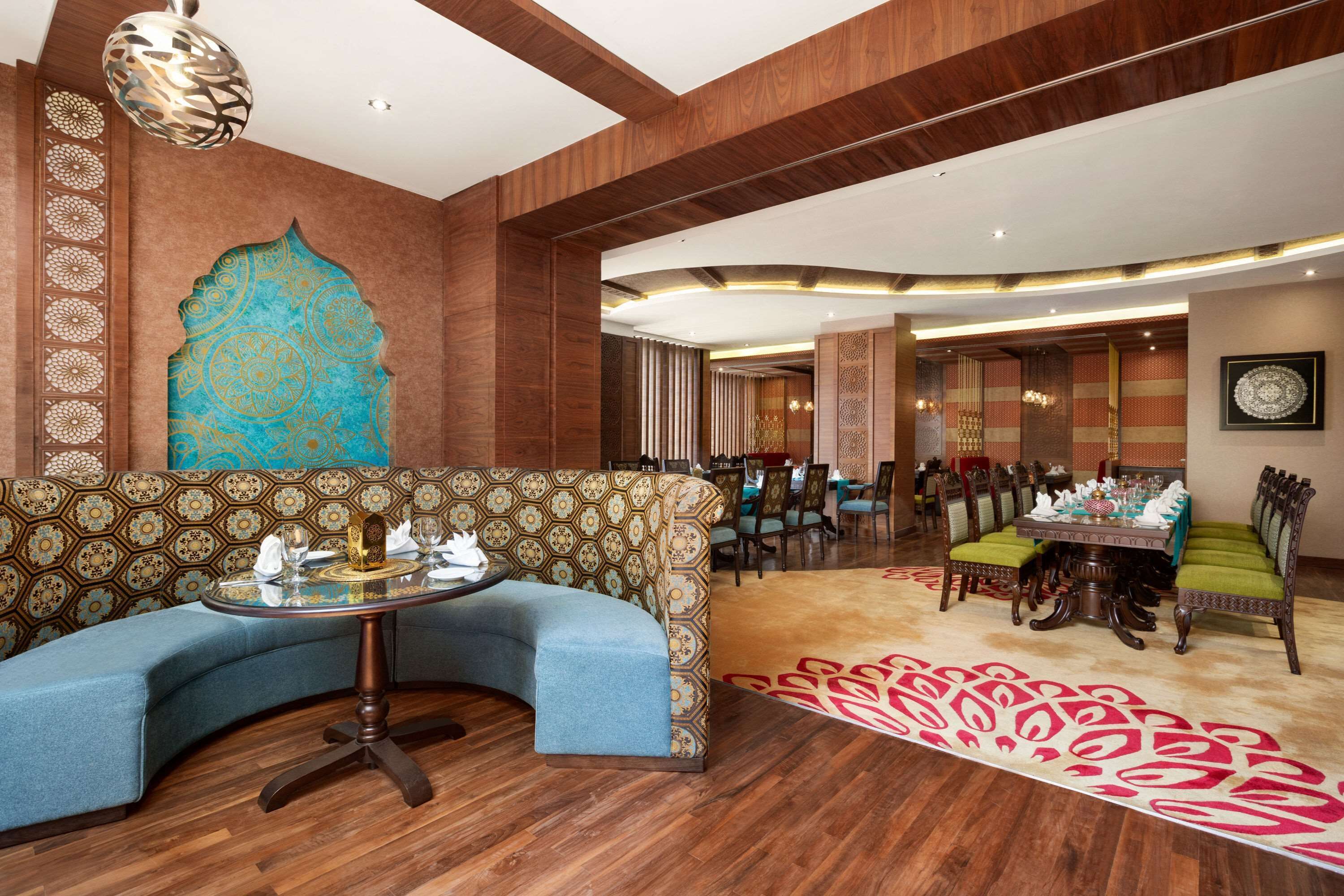 A modern hotel lobby with a curved sofa, a round table, and a dining area with chairs.