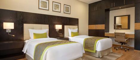 A hotel room with two beds, a desk, and a chair.