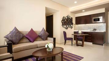 A modern living room with a sofa, coffee table, and a dining area with a chair and table.
