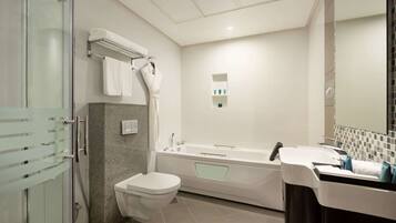 Un baño moderno con cabina de ducha de vidrio, inodoro blanco, bañera independiente y tocador con espejo.
