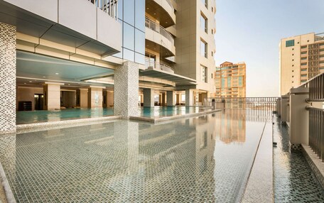 A modern hotel with a large indoor swimming pool, multiple floors, and balconies.