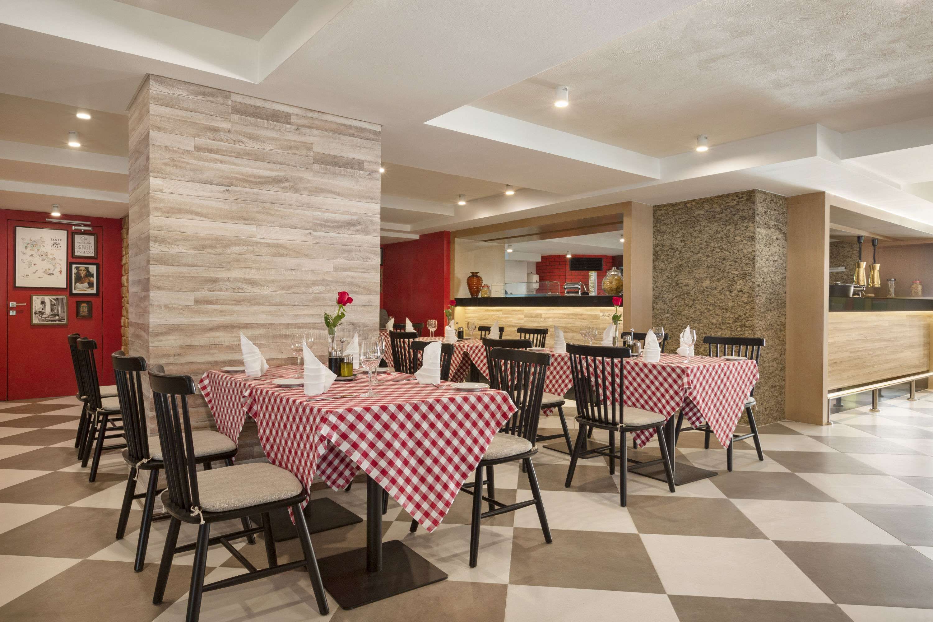 Un espace repas avec des nappes à carreaux, des chaises noires et un pilier central.