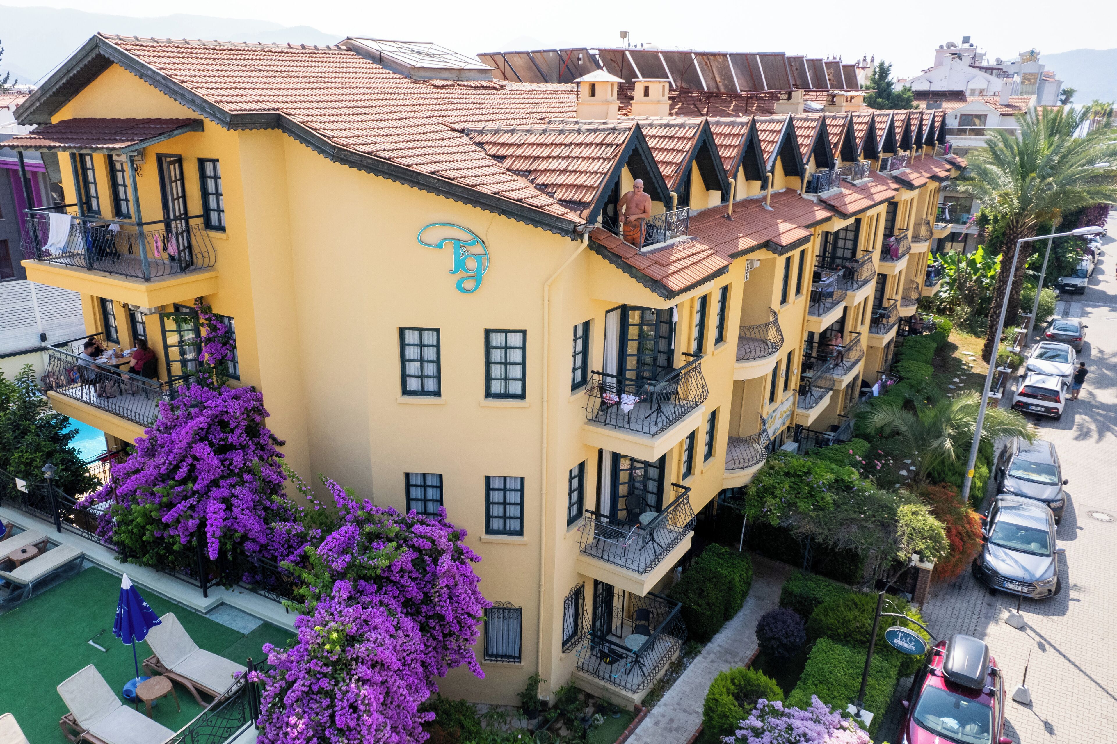A multi-story hotel with balconies, a swimming pool, and lush landscaping.