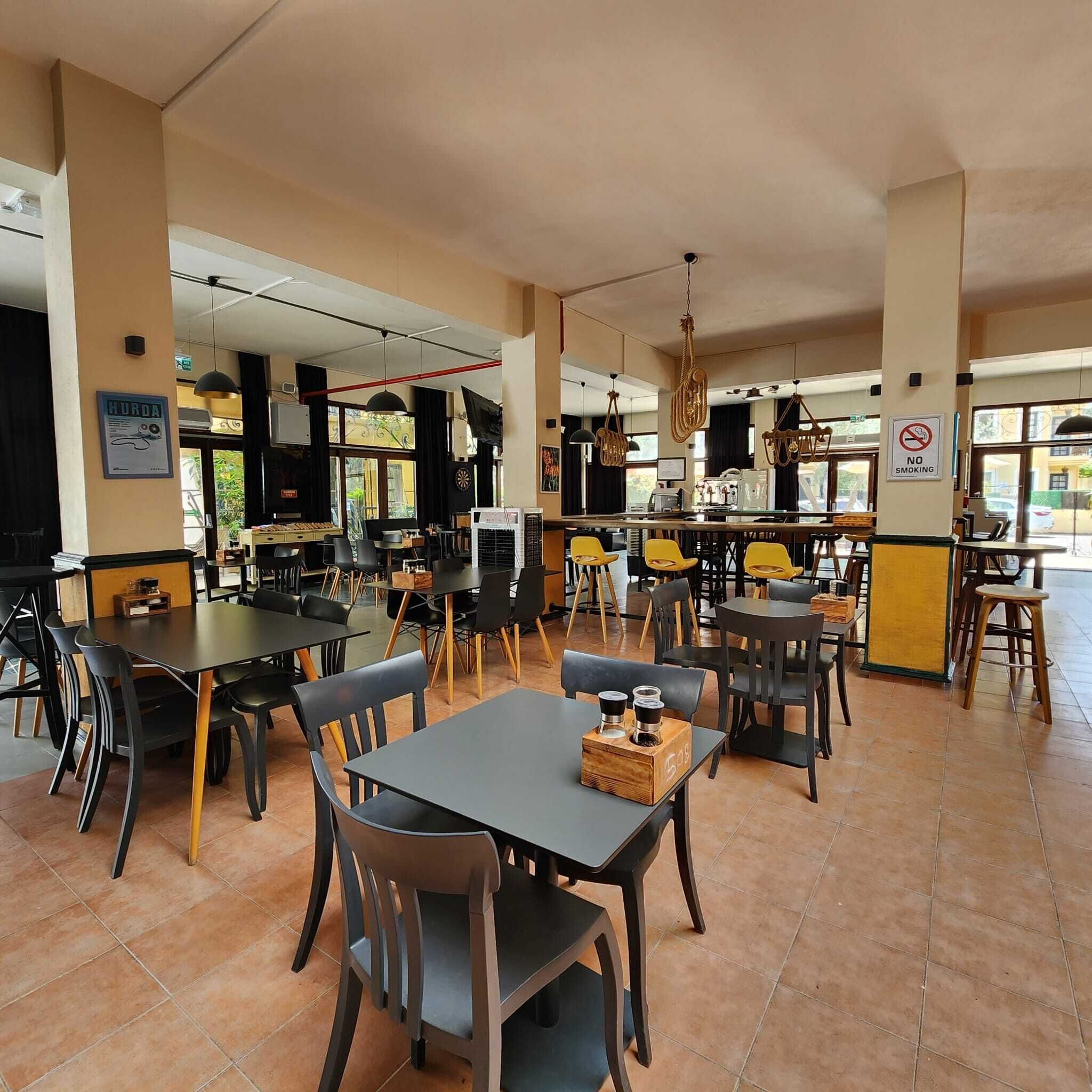 A restaurant with multiple tables and chairs, a kitchen area, and a 'NO SMOKING' sign.