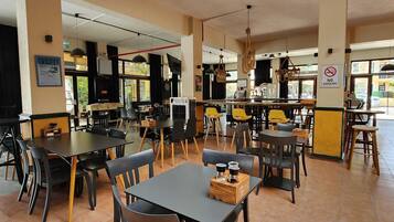 A restaurant with multiple tables and chairs, a kitchen area, and a 'NO SMOKING' sign.