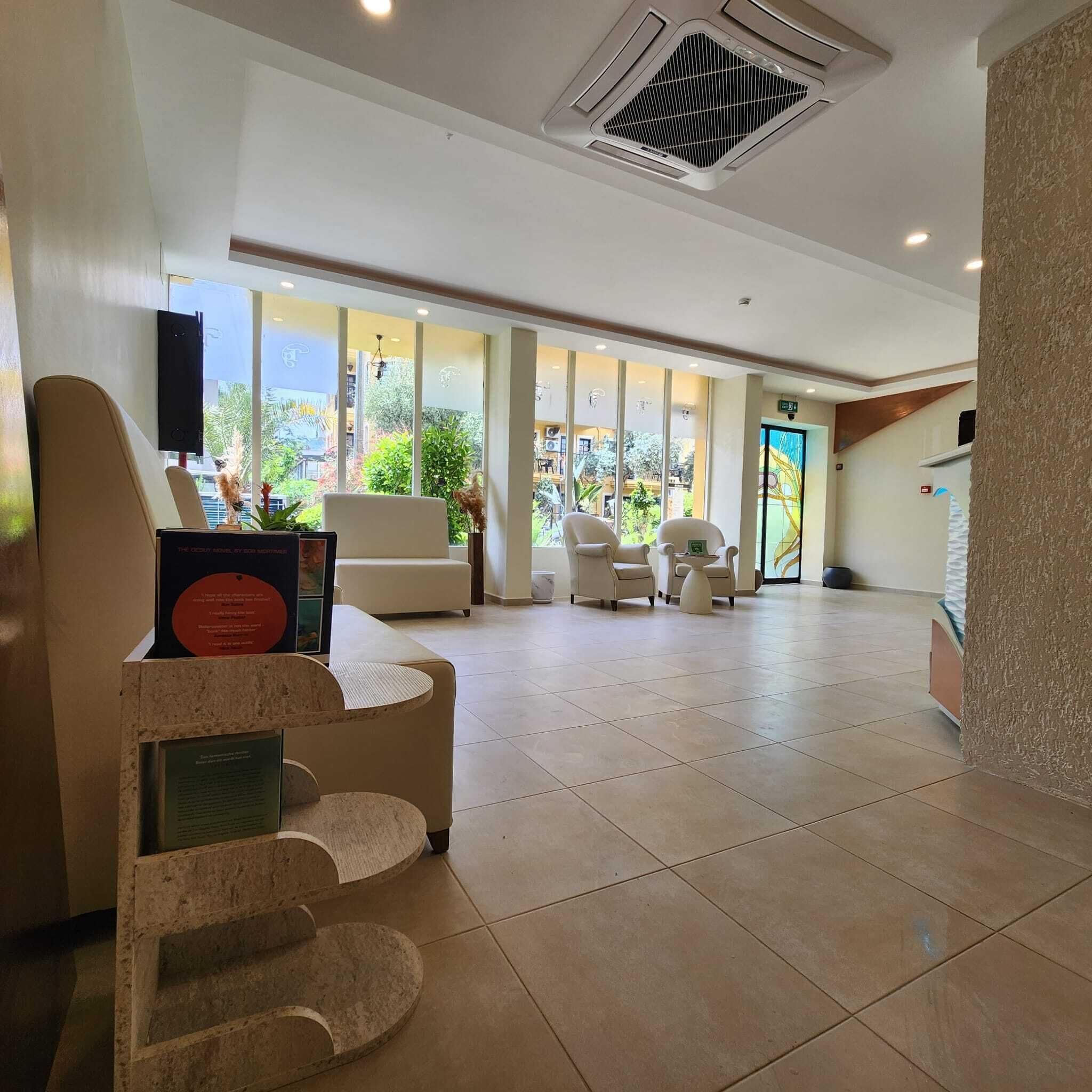 Un hall espacioso con mostrador de recepción, zona de estar y grandes ventanales que ofrecen vistas al exterior.