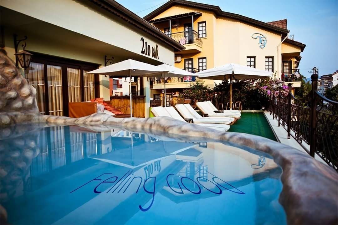 Un hotel con piscina, bar y mobiliario exterior.