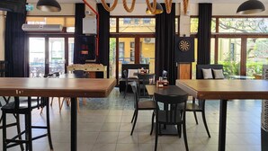 A restaurant with wooden tables and chairs, a hanging rope light fixture, and a dartboard on the wall. - T & G Apartments (Marmaris)