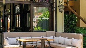 An outdoor seating area with a sofa and tables, surrounded by greenery and architectural details. - T & G Apartments (Marmaris)