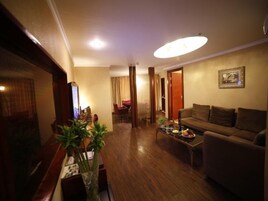 A living room with a sofa, a coffee table, a TV, and a plant.