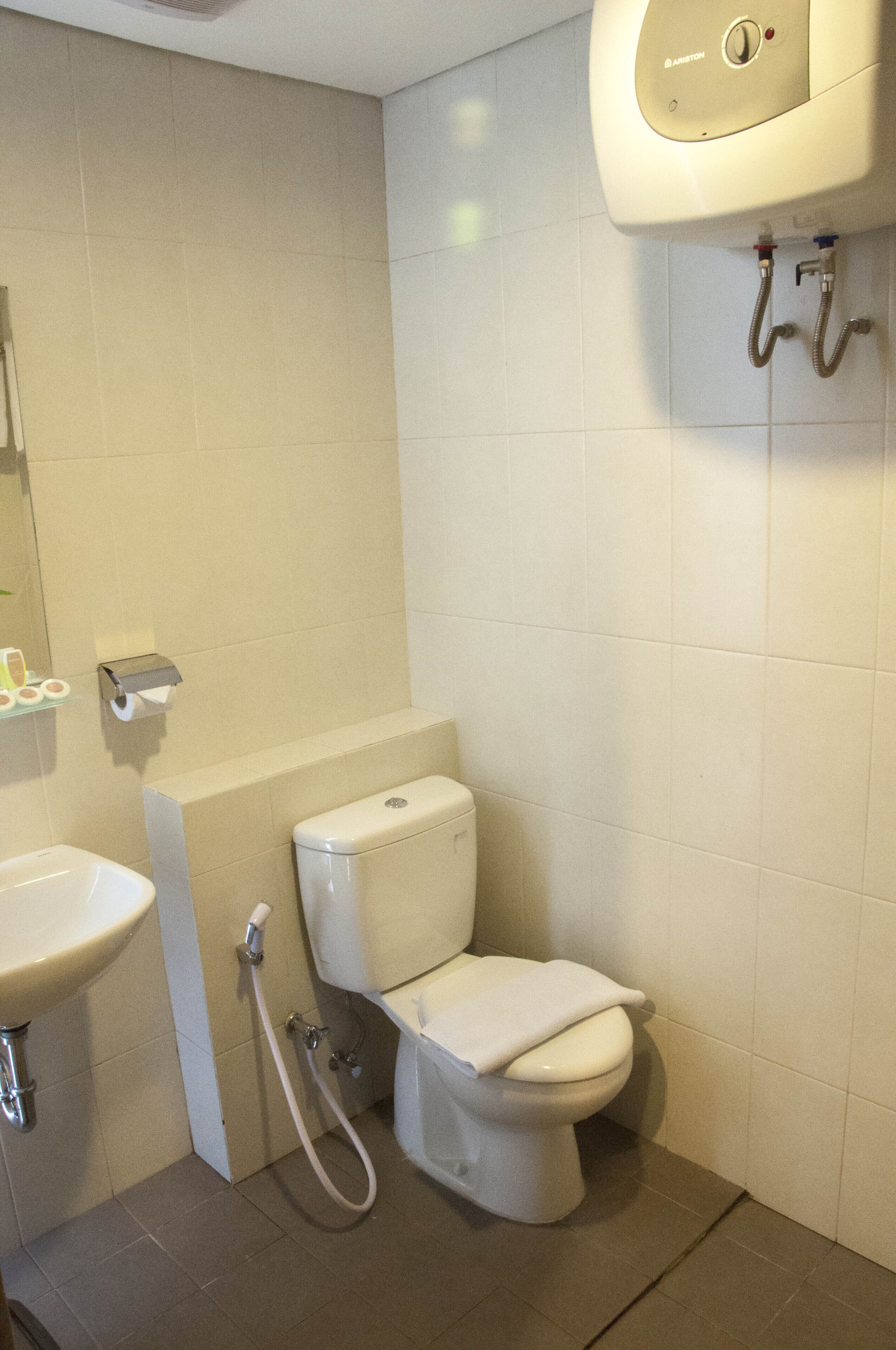 Une salle de bain équipée de toilettes, d’un lavabo et d’un sèche-mains fixé au mur.