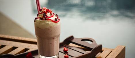 A glass of smoothie on a wooden tray with a blurred background.