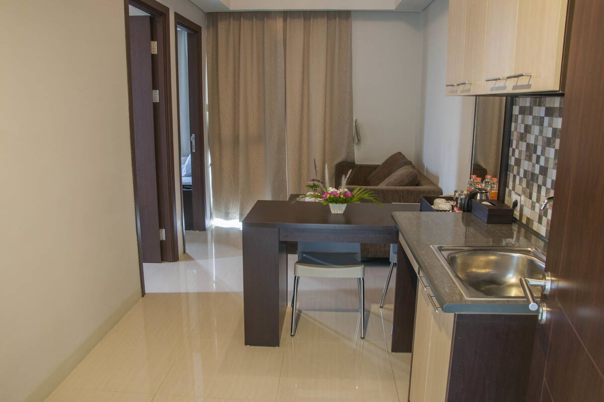 A modern kitchen with a dining table, a built-in sink, and a sofa in the background.