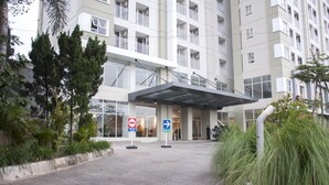 A modern building with a covered entrance, a no parking sign, and directional signs. - Sahid Skyland City Jatinangor Hotel (Hegarmanah)