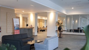 A modern lobby with a reception desk, seating area, and large windows. - Sahid Skyland City Jatinangor Hotel (Hegarmanah)
