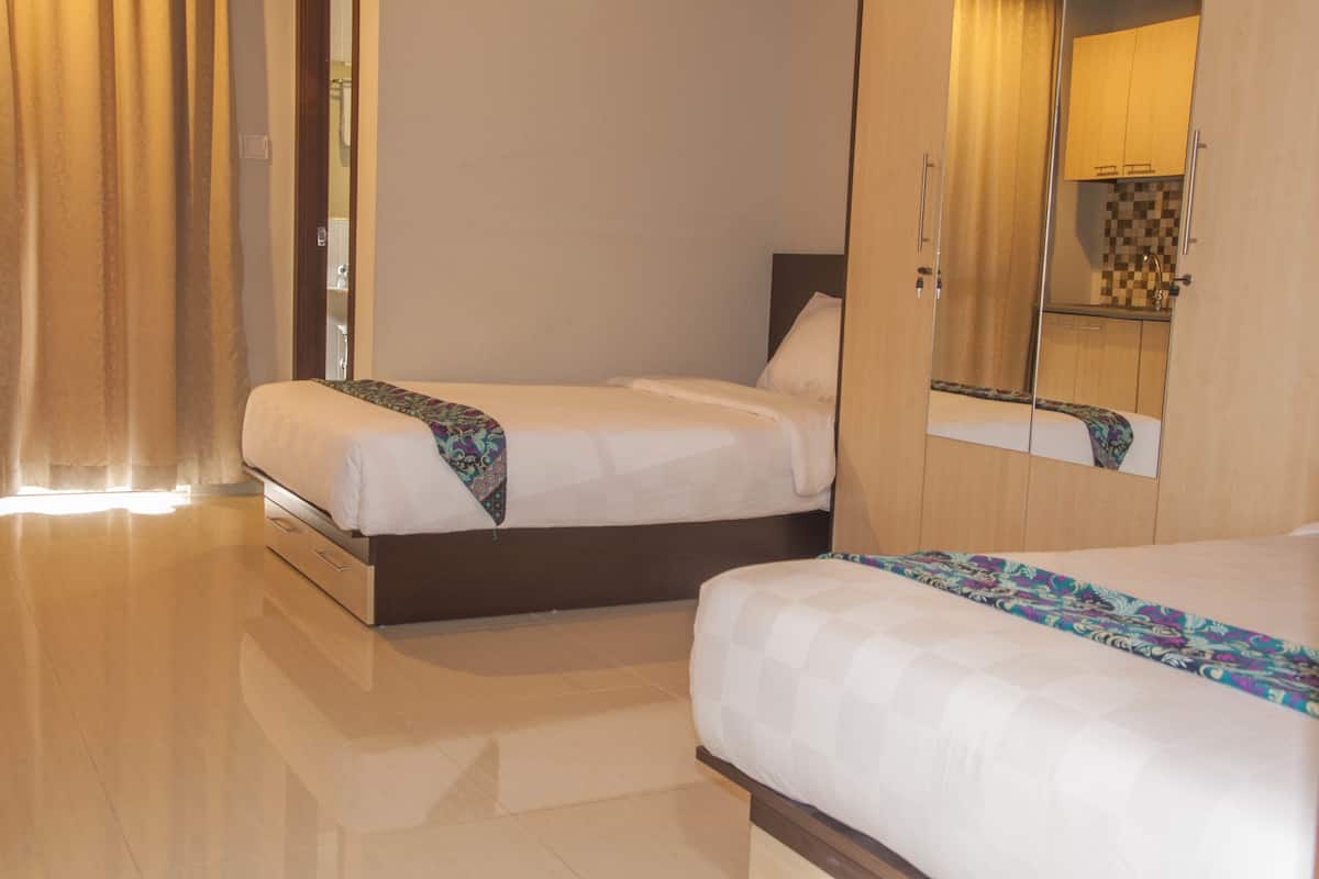 A hotel room with two beds, a large mirror, and a visible bathroom area.