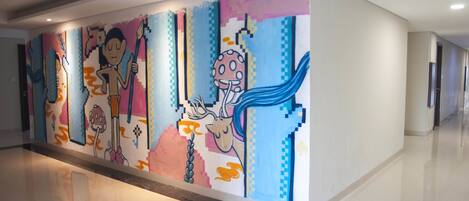 A hallway with a colorful mural featuring abstract figures and patterns.