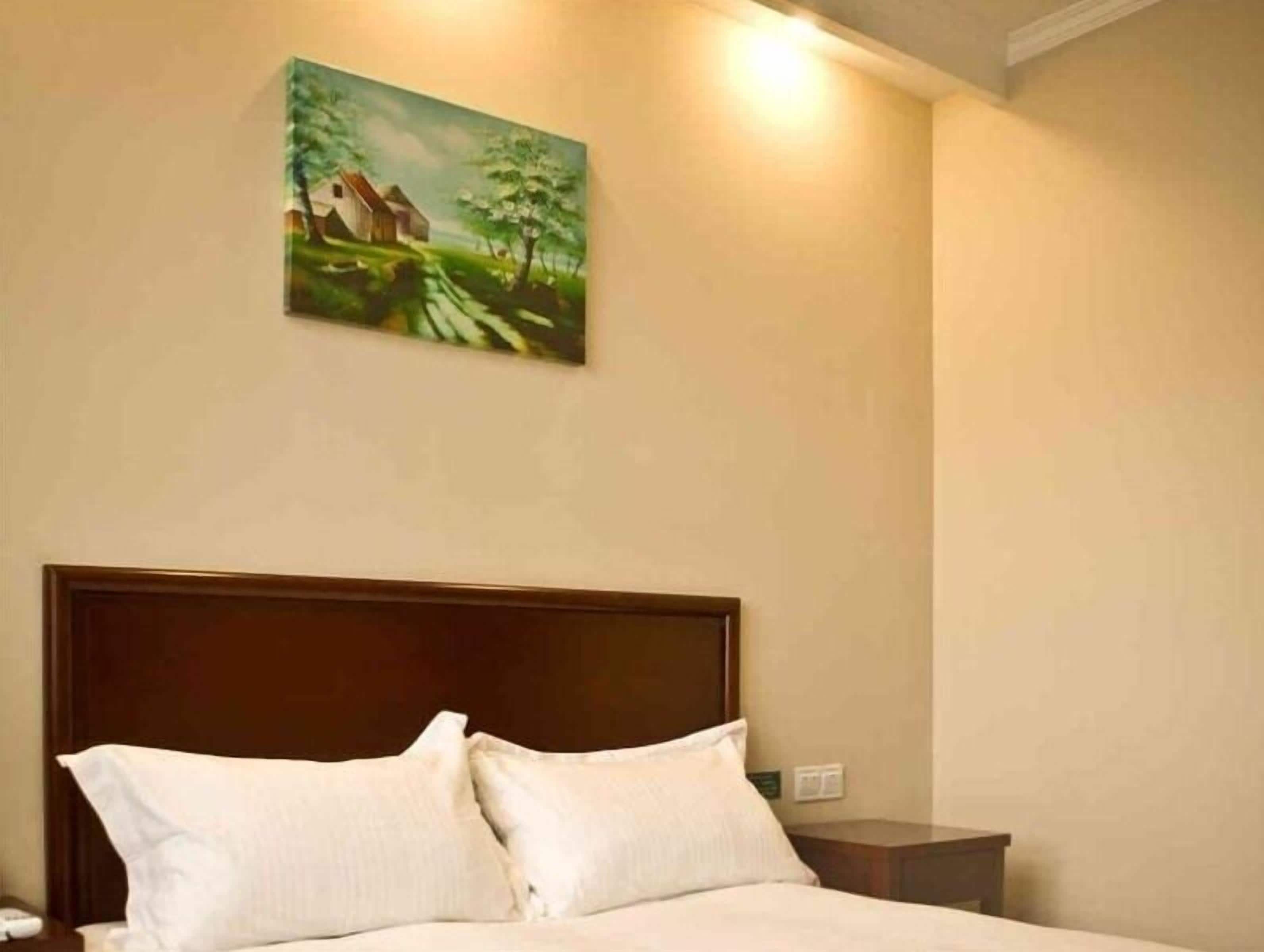 A hotel room with a bed, a nightstand, and a painting on the wall.