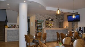 A modern restaurant with wooden furniture, a bar area, and a TV mounted on the wall. - Villa Arte (Ohrid)