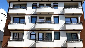 A multi-story building with balconies, a wooden front door, and a clear sky. - Villa Arte (Ohrid)
