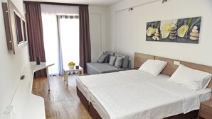 A hotel room with a large bed, a desk, a sofa, and a painting on the wall. - Villa Arte (Ohrid)