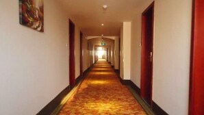 En hotellkorridor med ett mattbeklätt golv, dörrar på båda sidor och en tavla på väggen till vänster.