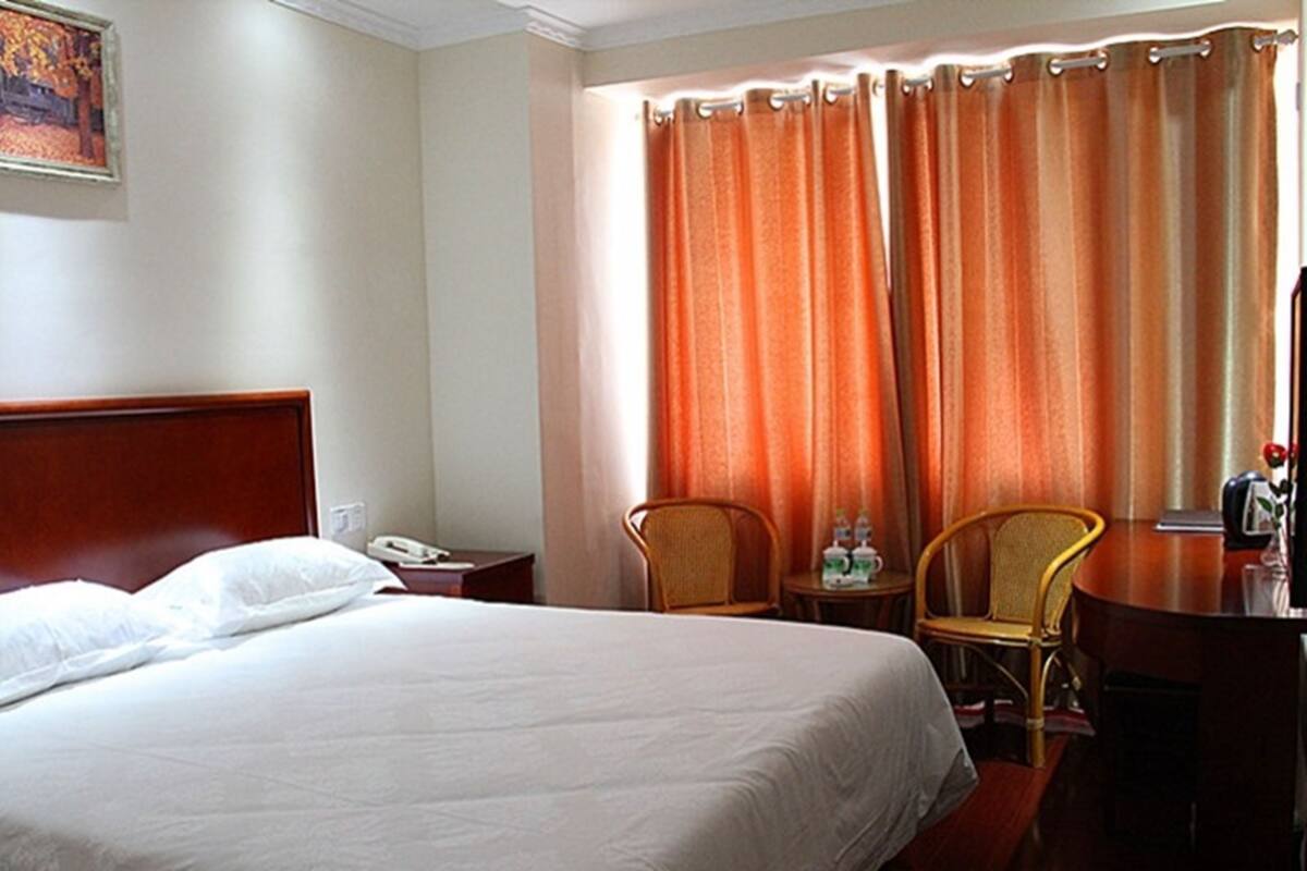 Ein Hotelzimmer mit einem großen Bett, zwei Sesseln, einem Schreibtisch und einem fensterbepflanzten Fenster.