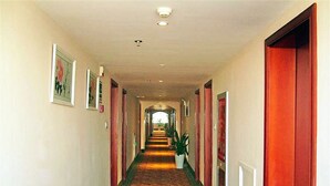 A long, narrow hallway with a carpeted floor, flanked by doors on both sides. - GreenTree Inn Huaian West Huaihai Road Hotel (Huai'an)