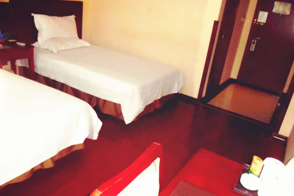 A hotel room with two single beds, a small table with a tray of items, and a wooden chair.