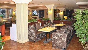 A restaurant with high ceilings, patterned upholstery, and a central column. Tables are arranged around the column, with chairs and a small seating area. - GreenTree Inn Bengbu Longhu Express Hotel (Bengbu)