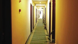 A long, narrow hotel corridor with a green carpet, yellow walls, and doors on both sides. - GreenTree Inn Bengbu Longhu Express Hotel (Bengbu)