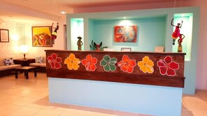 A reception desk with a floral design, a sofa, a lamp, and artwork on the walls.
