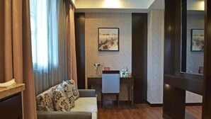 Une chambre d’hôtel avec un canapé, un petit bureau et un tableau au mur.