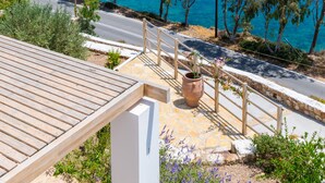 A coastal view with a road, trees, and a clear blue sea. - Allotina Houses (Patmos)