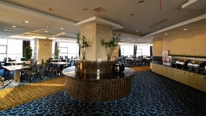 Een hotel lobby met een centraal receptiebalie, meerdere zithoeken en een buffet.