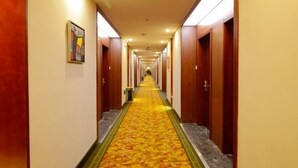 A hotel hallway with a carpeted floor, wooden doors, and a long corridor.