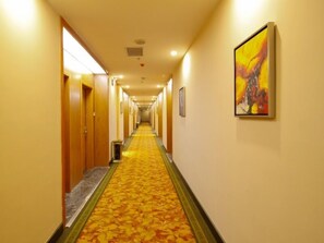 Ein Hotelgang mit Teppichböden, Holztüren und einem Gemälde an der Wand.