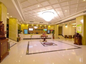 Eine Hotelhalle mit einer Rezeption, einer Kristallleuchter und einem dekorativen Mittelstück.