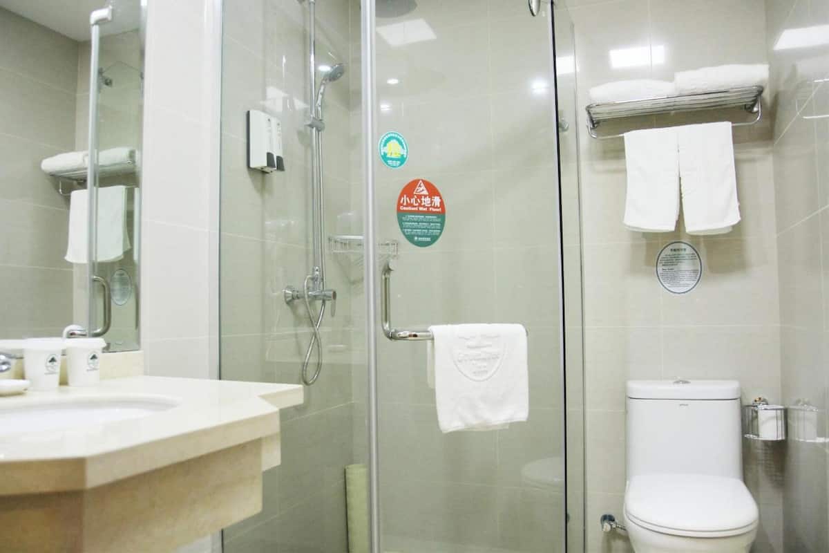 A modern bathroom with a glass-enclosed shower, a toilet, and a sink with a mirror.