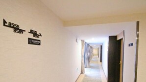 Un couloir d’hôtel avec des panneaux d’orientation et un sol recouvert de moquette.